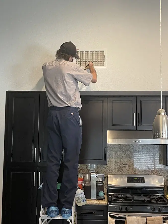 Technician inspecting an air vent during HVAC service in Corning